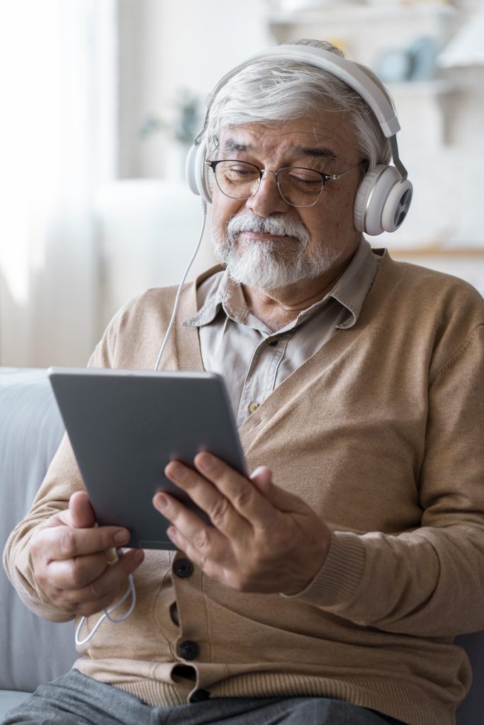 old man wearing headphones and looking at a tablet