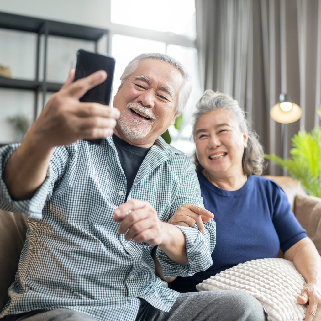 Older Asian couple taking a selfie.